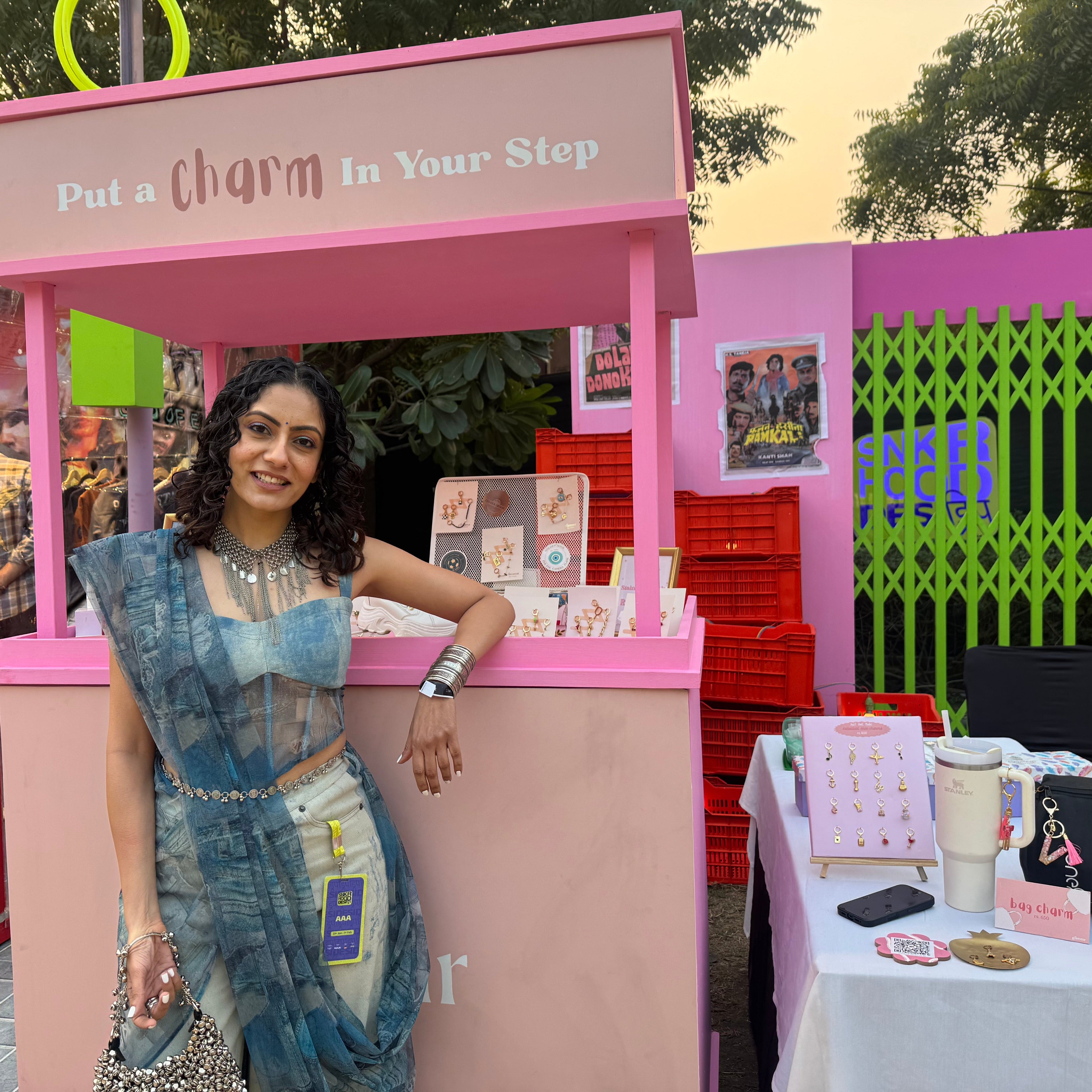 Suhana Sethi standing in front of a pink booth with 'Put a Charm In Your Step' text at our SNKRHOOD pop up.